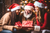 Two young women and their dad with red Santa hats smiling and happily exchanging gifts enjoying their time together.